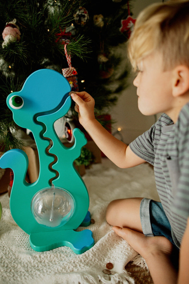 boy putting coin into aqua dino big belly bank