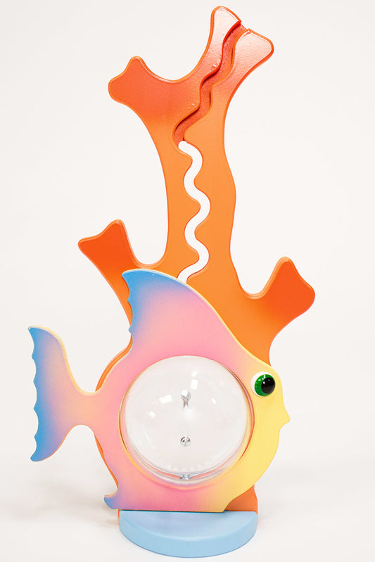 A colorful piggy bank in the shape of a fish airbrushed with pink, orange, and blue colors.