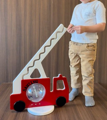 Child playing with a red fire truck piggy bank
